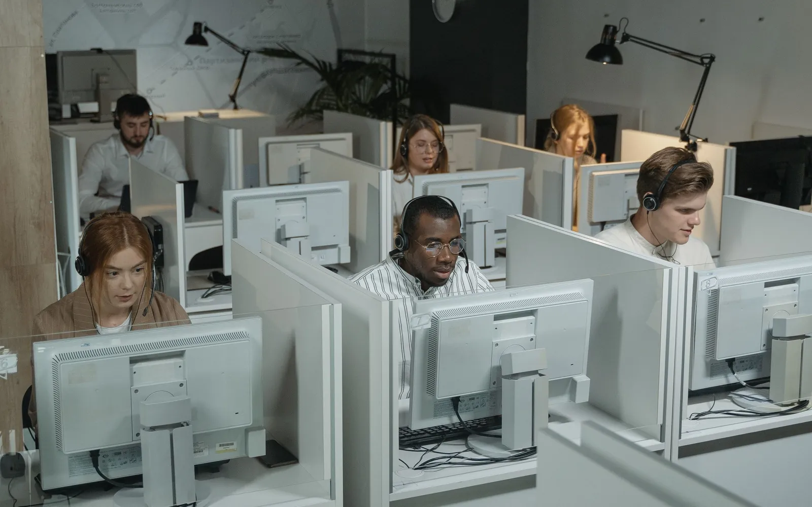 A customer support team working at computer stations with headsets