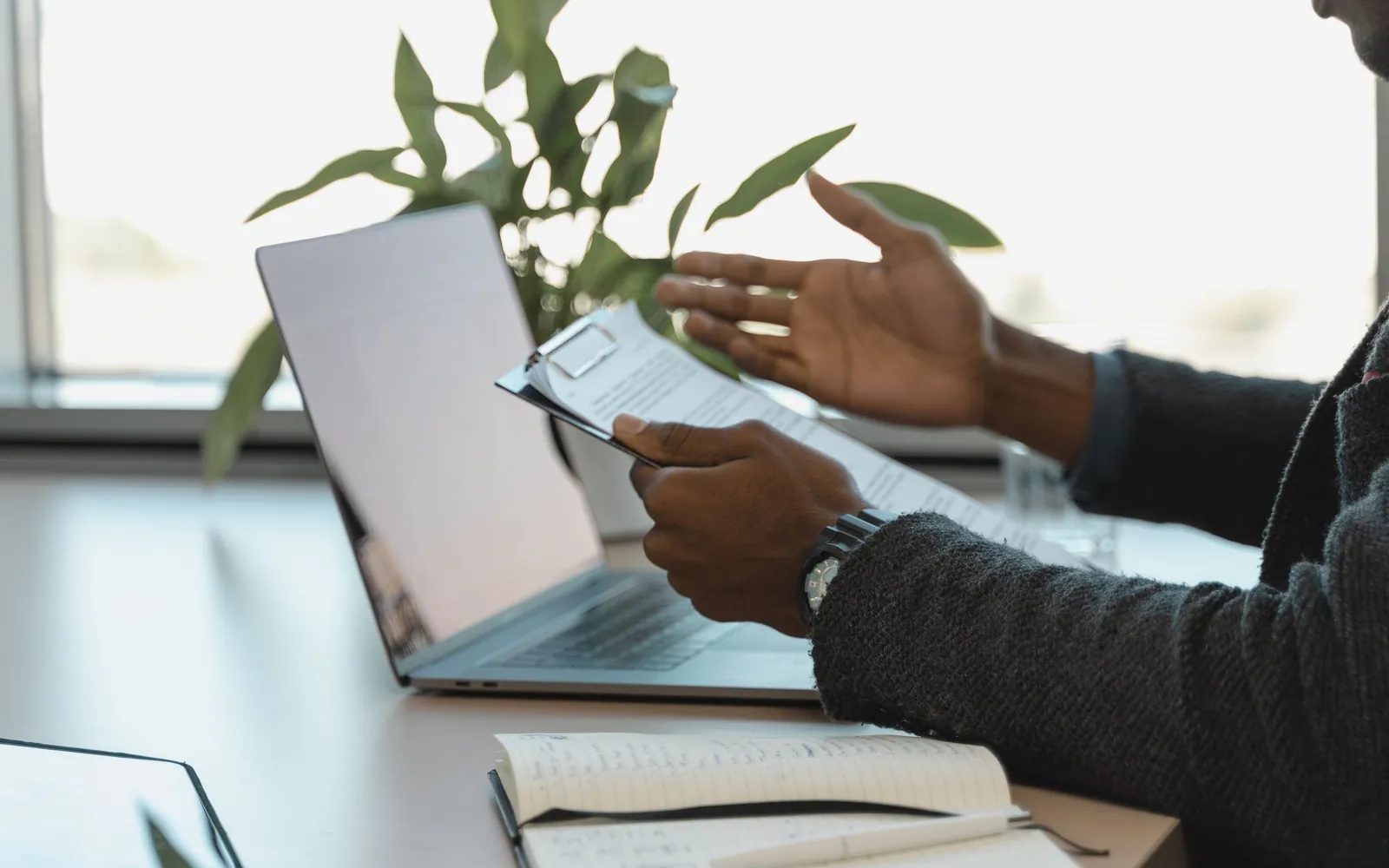 A professional reviewing documents beside a laptop and notebook