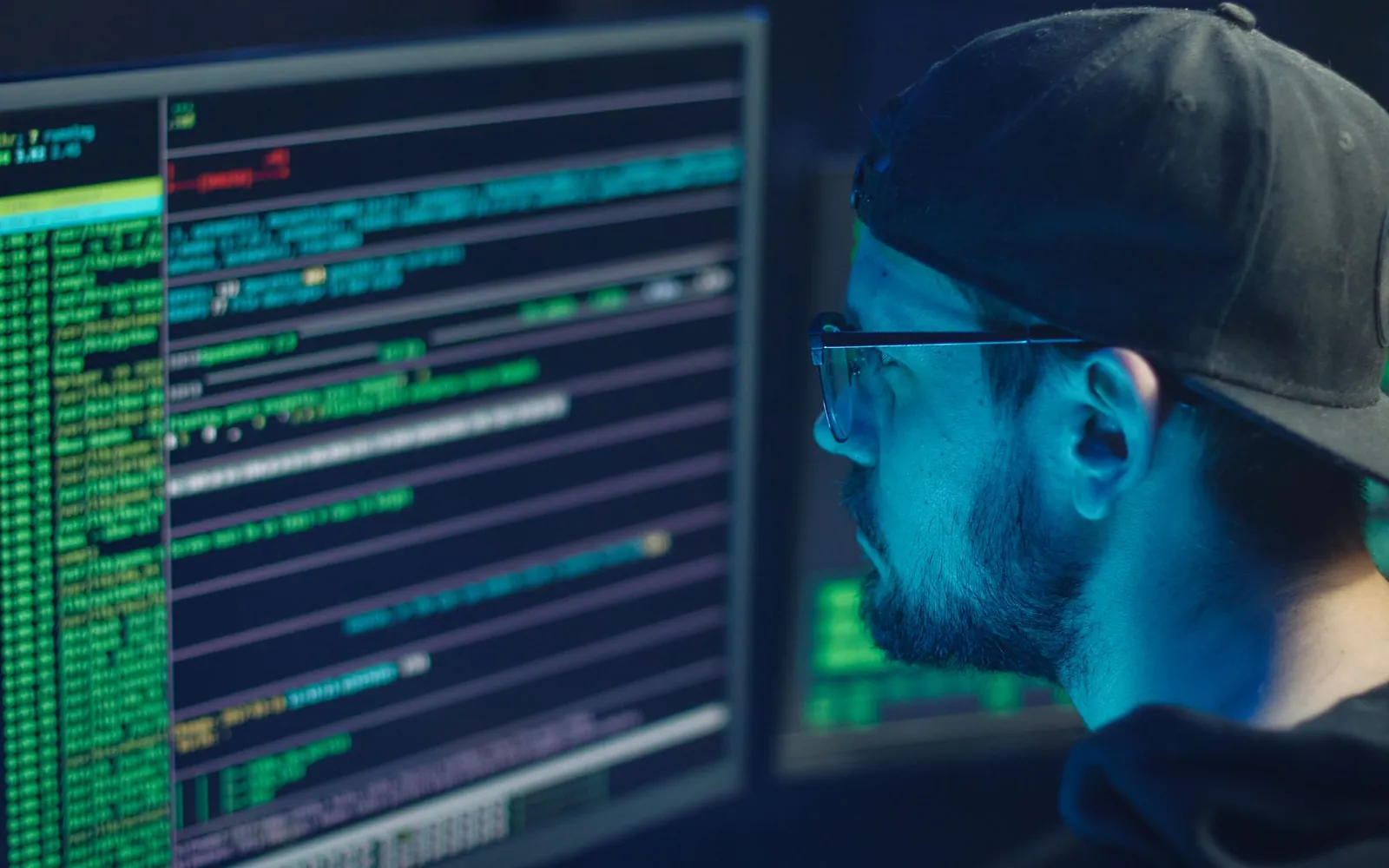 A security professional reviewing code across multiple monitors